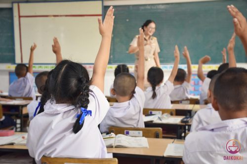 Students raising their hands to answer female teacher